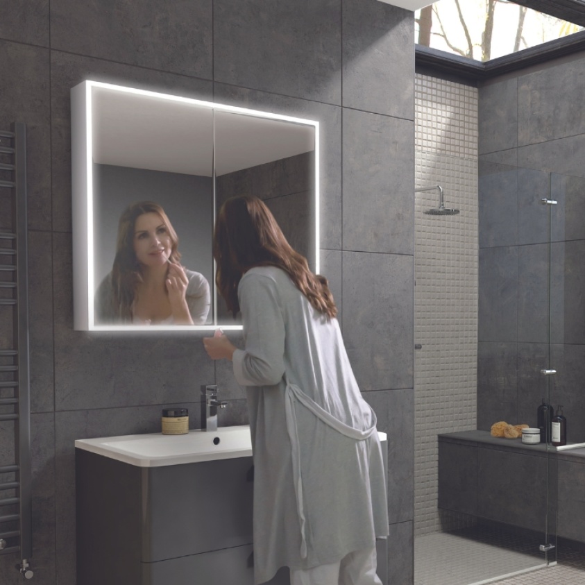 Product Lifestyle image of a woman checking her reflection in the HIB Qubic 800mm LED Mirror Cabinet